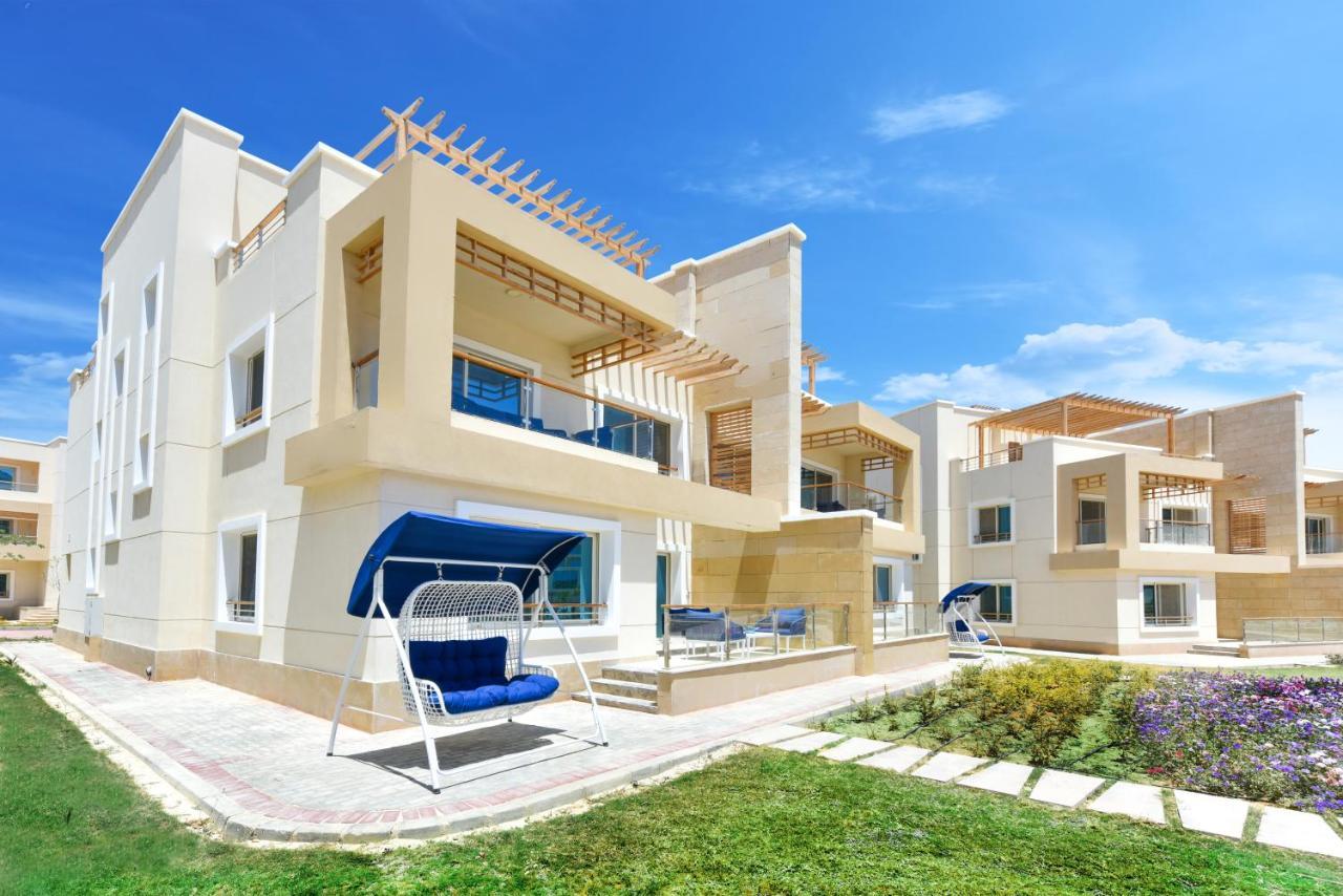 منتجع توليب الجلالة ماجستيك عين السخنة المظهر الخارجي الصورة The photo displays a modern residential complex featuring two or more white buildings with a contemporary architectural design. Each building has balconies, large windows, and a sunshine-friendly layout that maximizes natural light. In the foreground